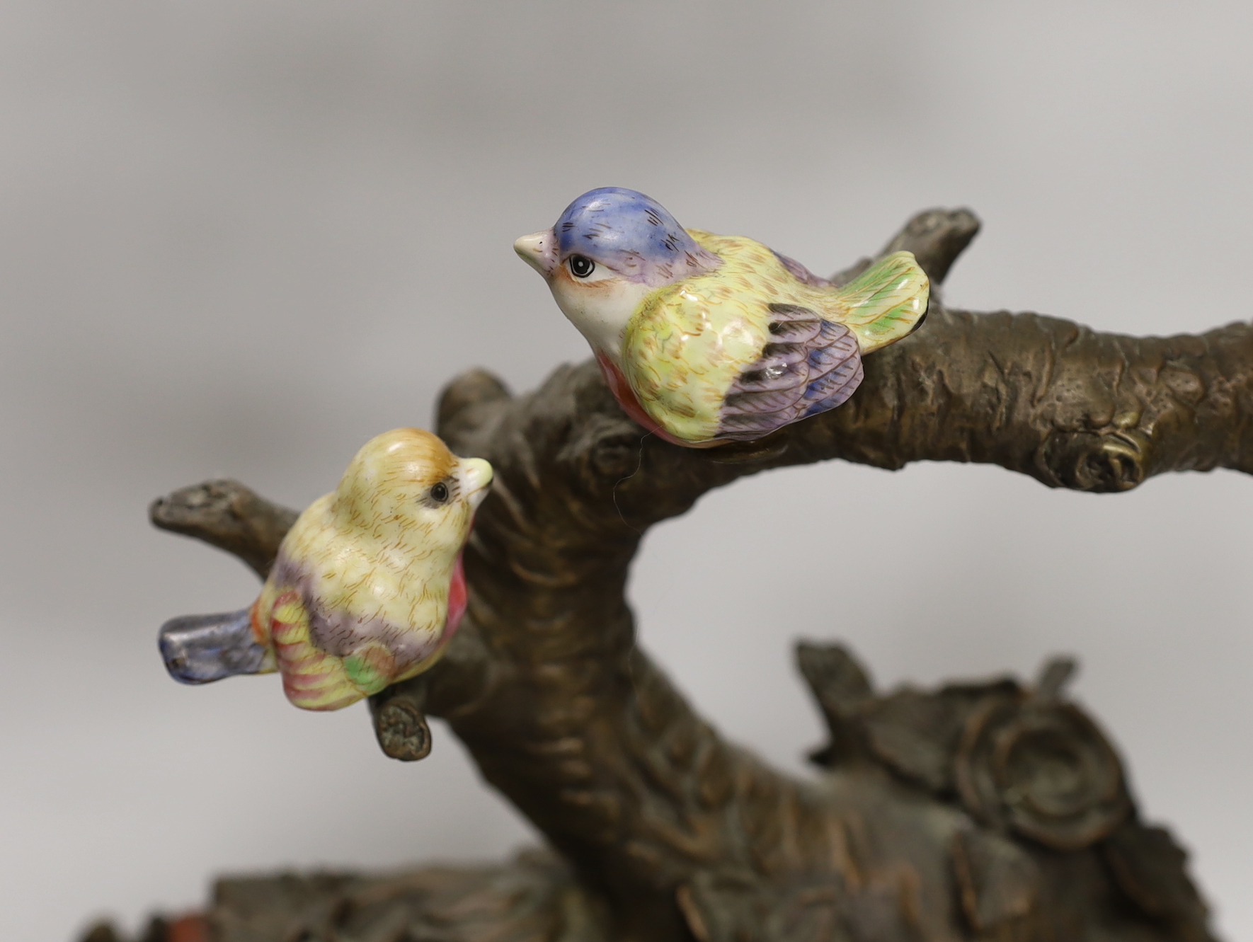 A pair of Victorian style bronzed metal and porcelain three branch candelabra, modelled as birds among branches, each 51cm high